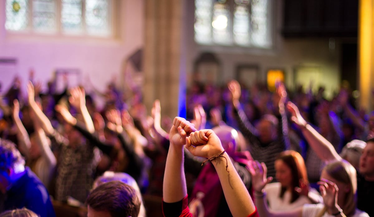 A congregation worship with raised hands at a Christian church service